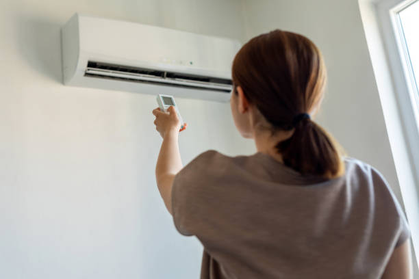mujer intentando encender aire acondicionado con mando que no responde